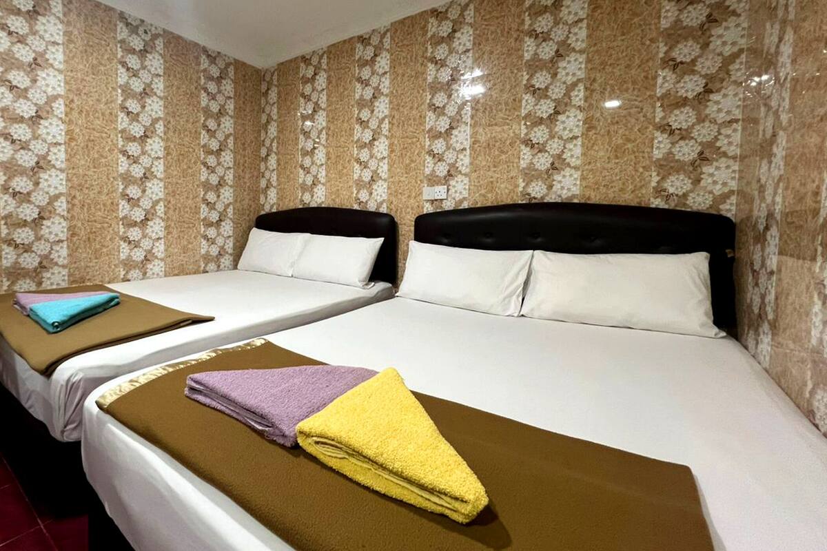 Camera d'albergo con due letti, ciascuno con testiera e cuscini. Sui letti ci sono degli asciugamani.