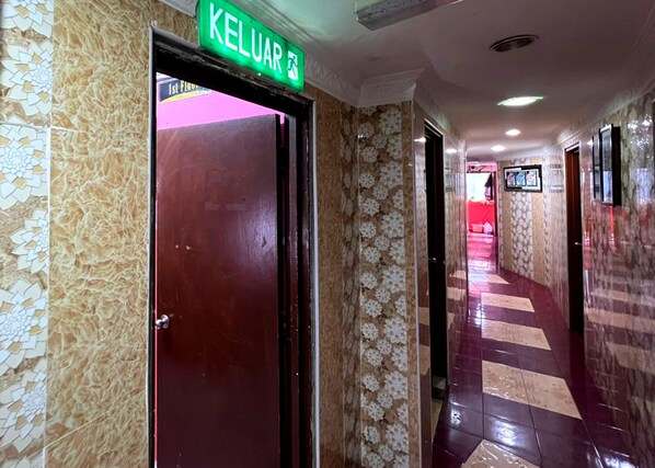 A hallway with a red door labeled 'KELUAR' and patterned walls.