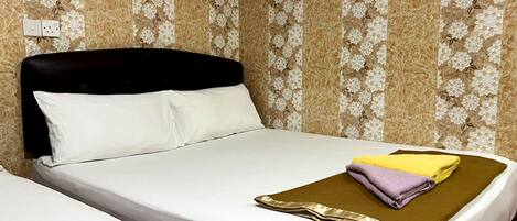 Una habitación de hotel con una cama, una mesita de noche y un papel tapiz floral en la pared.