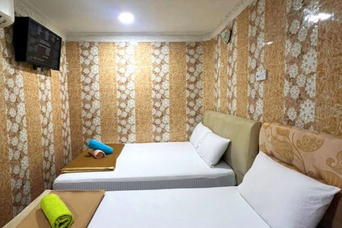 Een hotelkamer met twee bedden, een flatscreen televisie aan de muur en behang met een patroon.