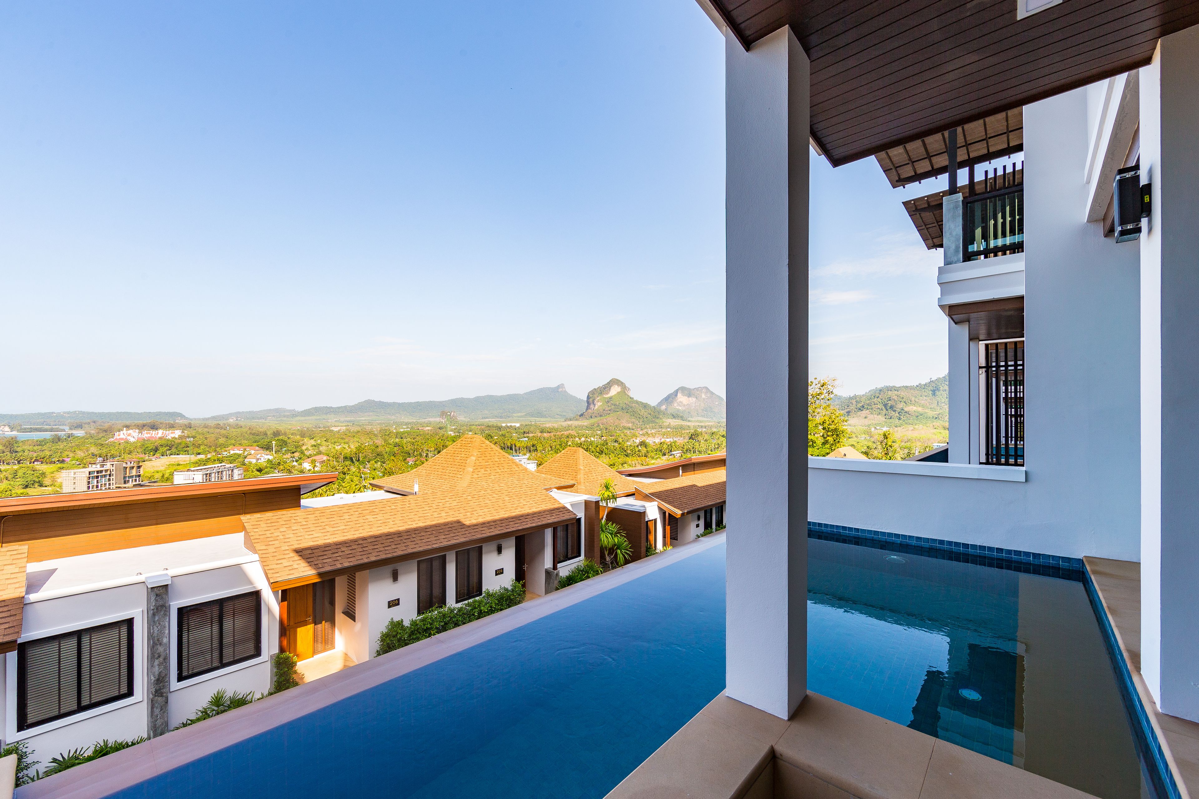 Ein modernes Hotel mit Dachpool und Infinity-Kante, das einen Blick auf entfernte Berge und eine üppige Landschaft bietet.