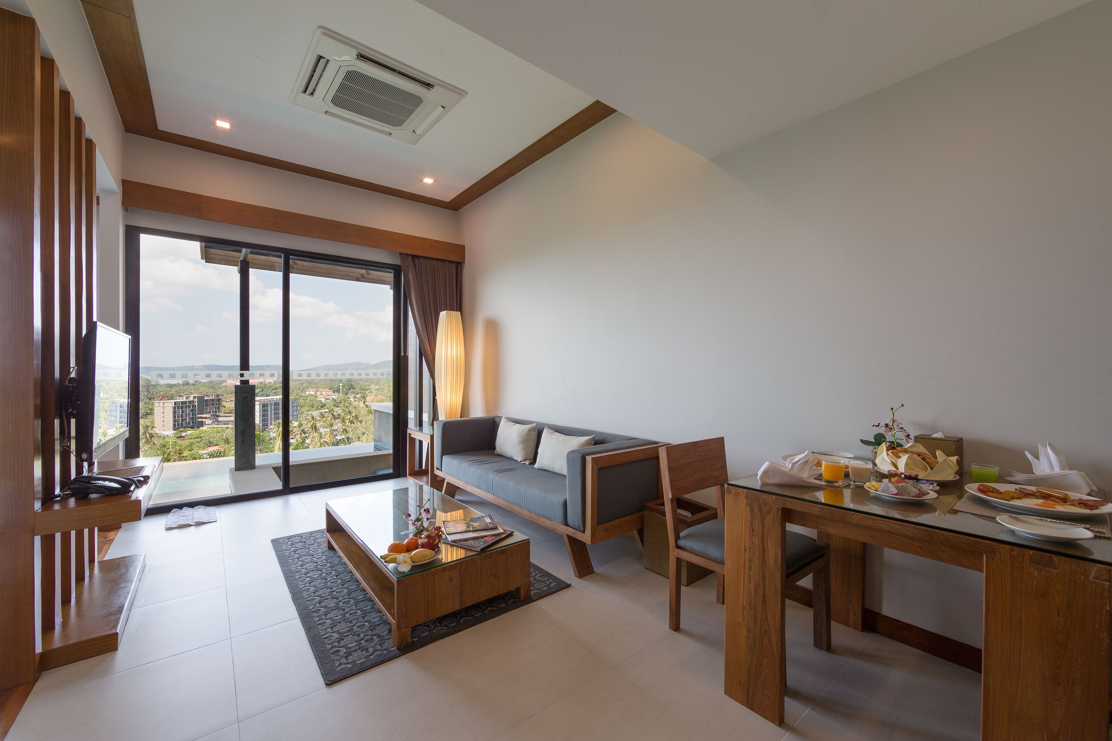 Una sala moderna con sofá, mesa de comedor y vistas de la ciudad a través de amplios ventanales.