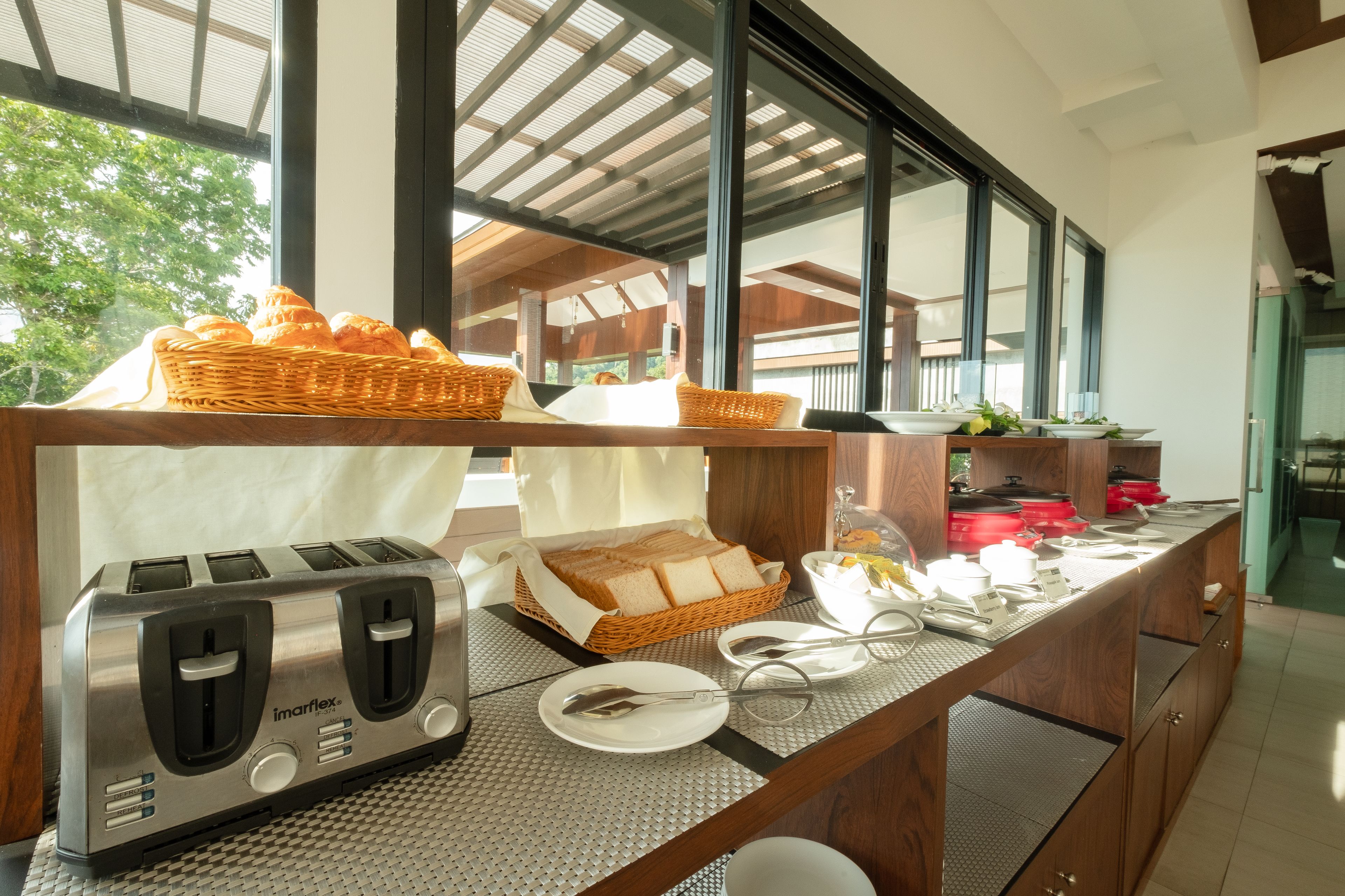 Mesa de desayuno buffet con un tostador, pan y platos.