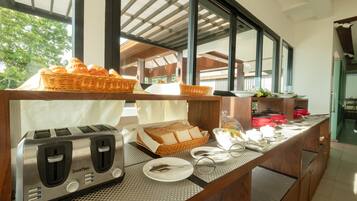 Mesa de desayuno buffet con un tostador, pan y platos.