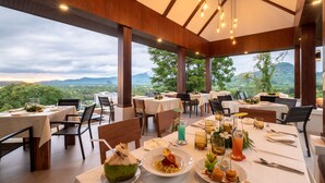 An outdoor dining area with tables set for meals, overlooking a mountainous landscape. - Andakiri Pool Villa Panoramic Sea View (Krabi)