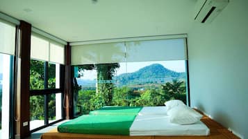 Ein Zimmer mit einem Bett, großen Fenstern und Bergblick.
