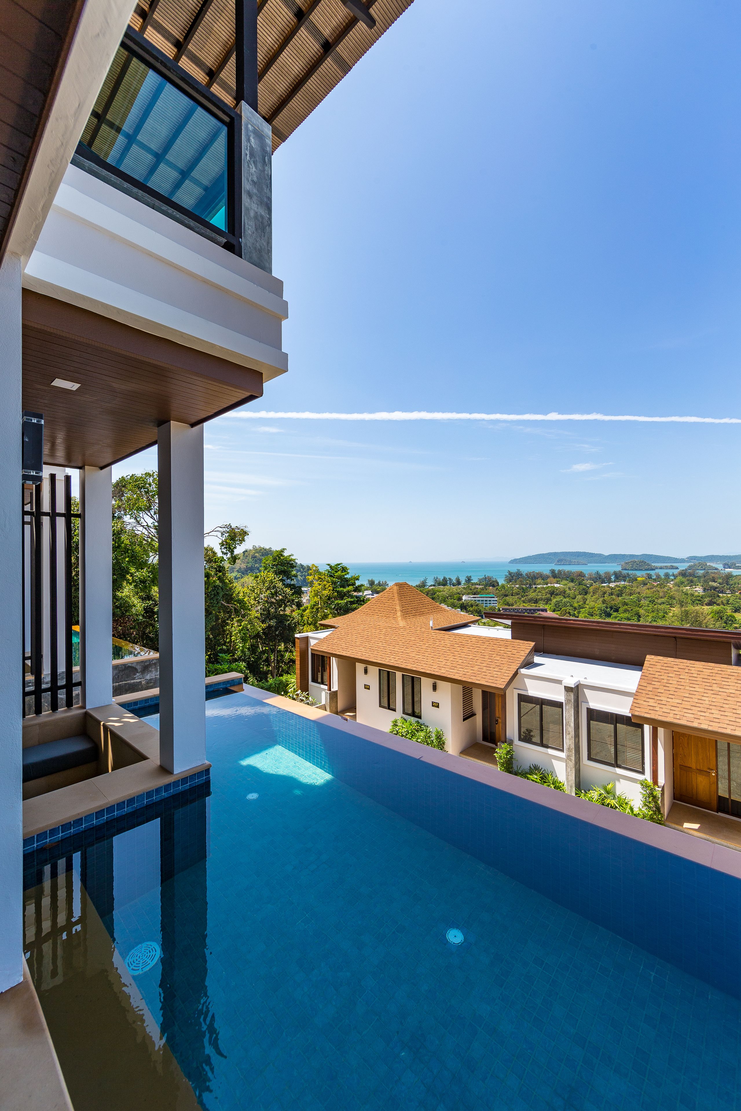A modern pool area with a clear view of the surrounding landscape, including a distant view of the sea and hills.