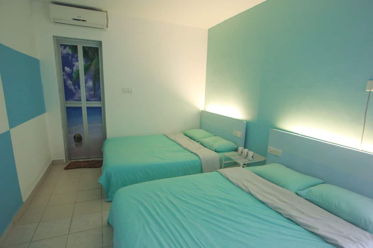 A room with two beds, a window with a view, and a wall-mounted air conditioner.