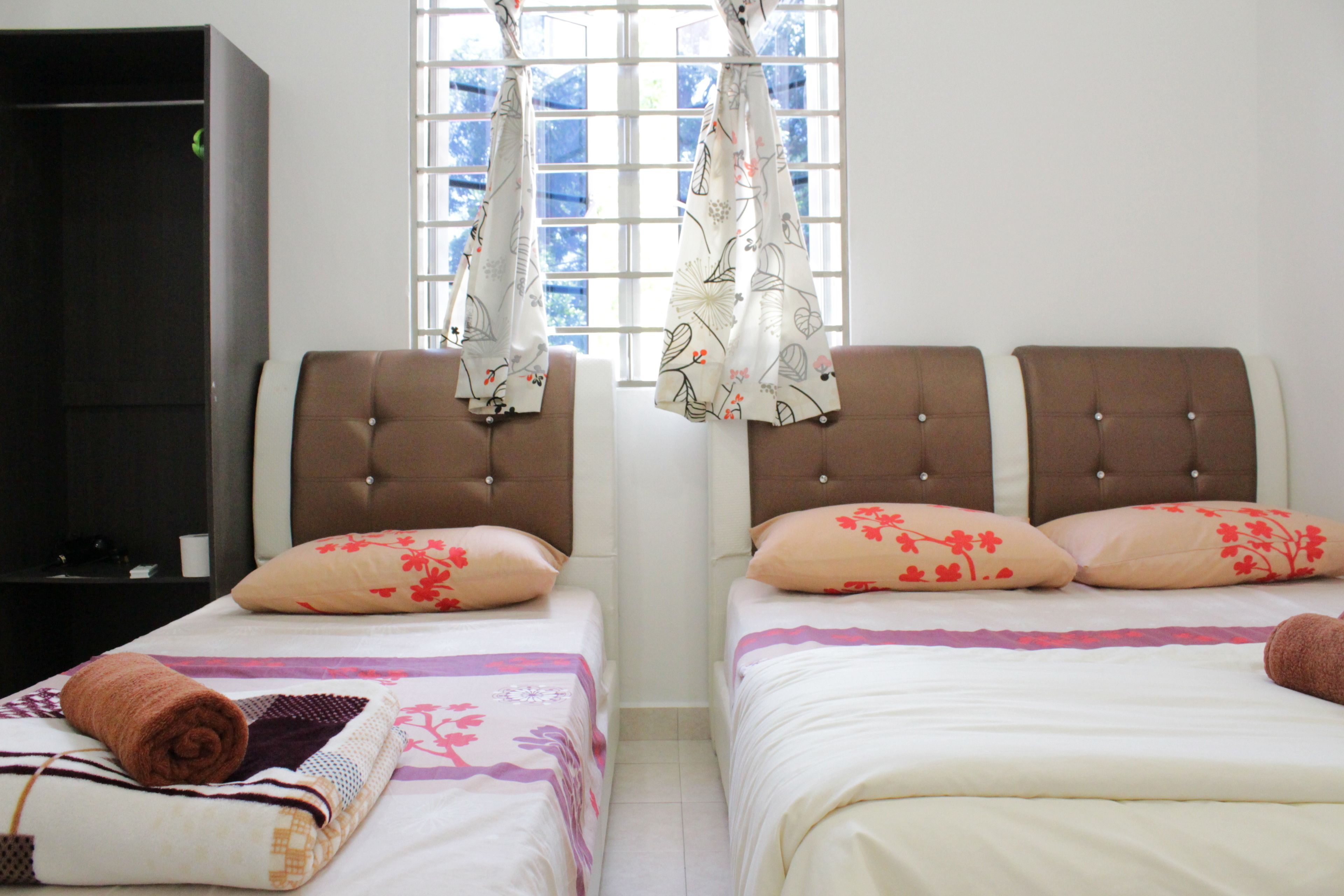 Un dormitorio con dos camas, cada una con cabecera, una ventana con cortinas y un armario.