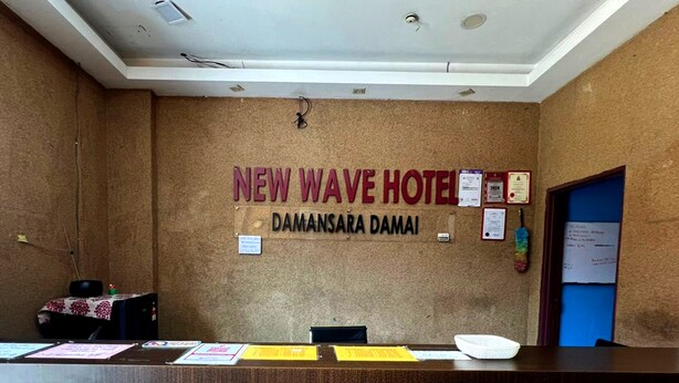 A reception desk at New Wave Hotel with a bulletin board displaying various notices.