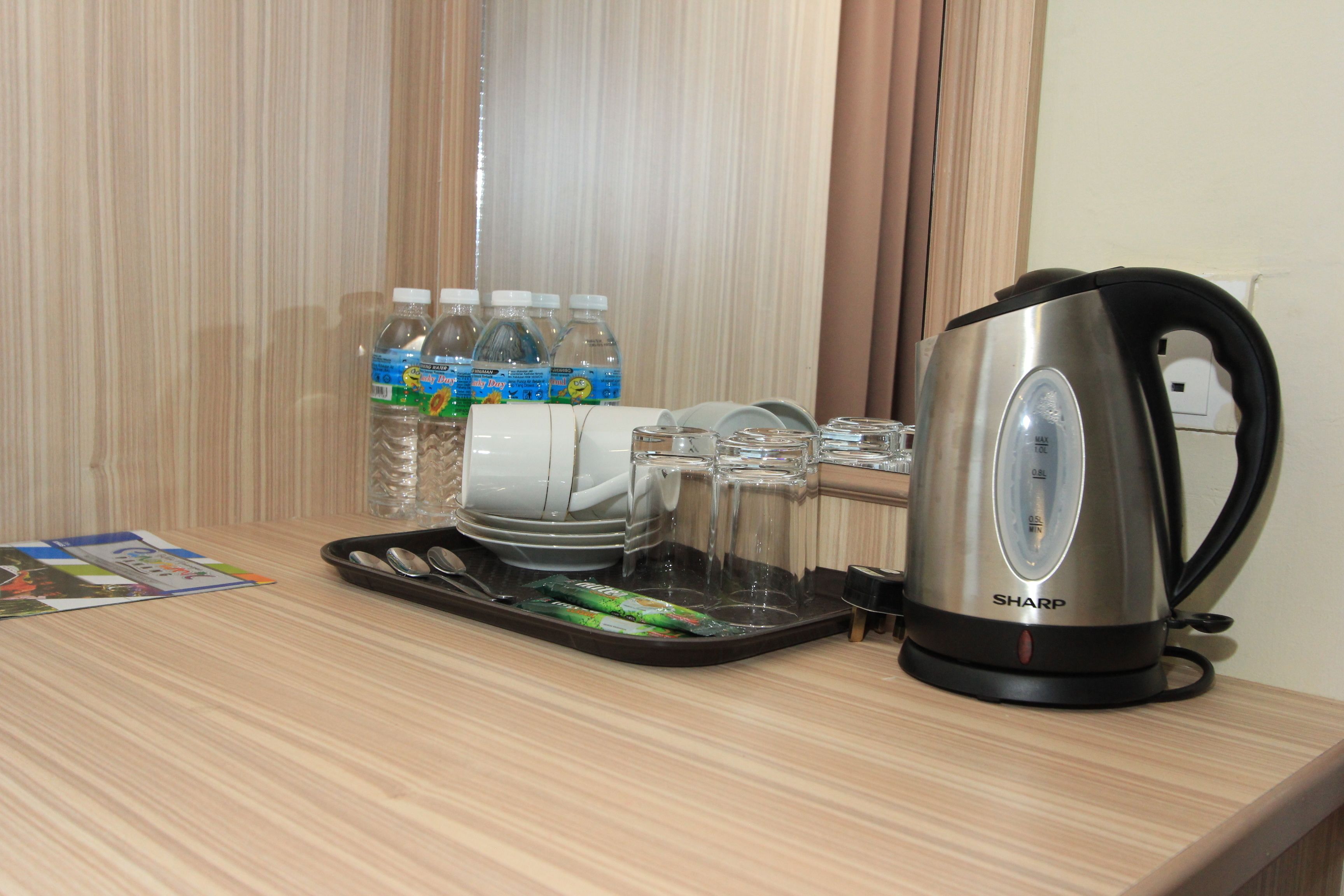 Una encimera de cocina con una tetera, botellas de agua, vasos y una bandeja con porciones de comida.