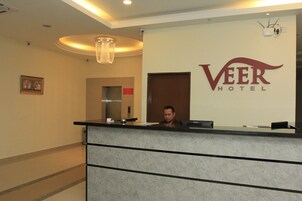 Un mostrador de recepción en el hotel Veer, con un diseño moderno, una araña y un cartel.