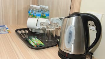 A kitchen area with a kettle, glasses, and bottled water.