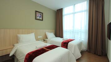 A hotel room with two beds, a wooden headboard, a window with curtains, and a framed picture on the wall.