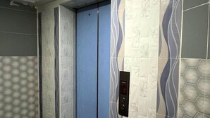 An elevator with a blue door, surrounded by patterned walls and a tiled floor.