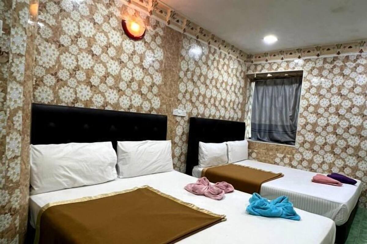 Camera d'albergo con due letti, carta da parati decorata e una finestra con tende.