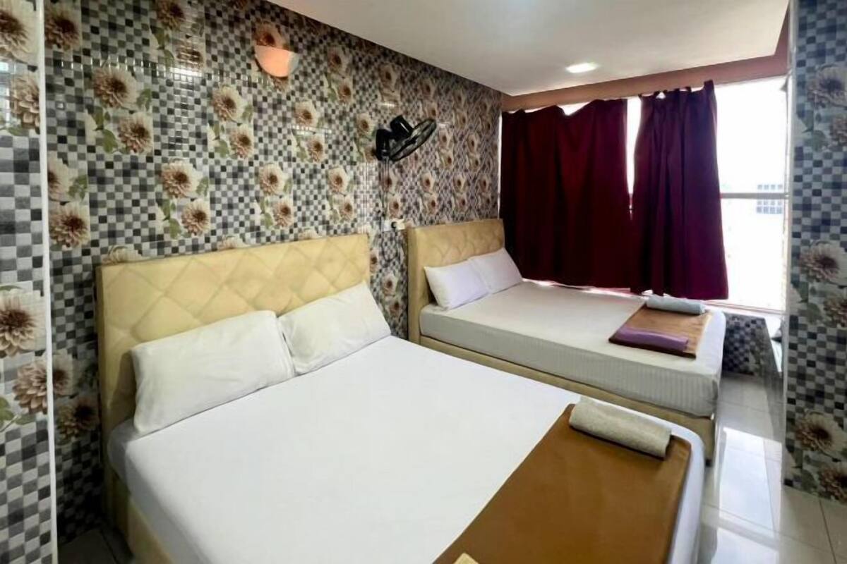 Camera d'albergo con due letti, pareti con motivo a scacchi, una finestra con tende e un lampadario a parete.
