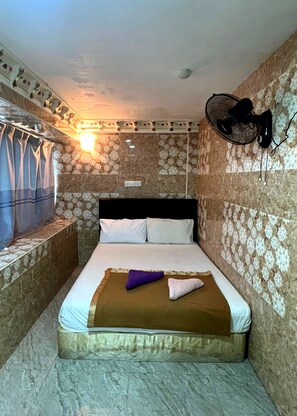 A small, cozy room with a bed, a wall-mounted fan, and a window with curtains. - New Wave Shah Alam Hotel (Shah Alam)
