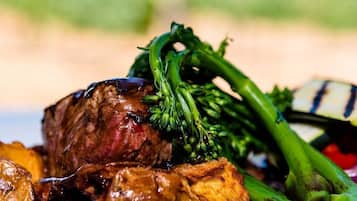 Un plato con un bistec, verduras verdes y una preparación a la parrilla.
