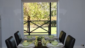 A dining table with four chairs, a glass top, and green bowls set with white napkins. - Vineyard Cottage at Upper Reach Winery (Baskerville)