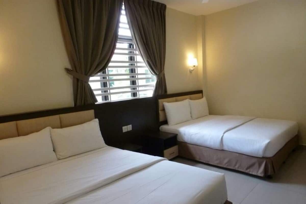 Ein Hotelzimmer mit zwei Betten, einem Fenster mit Vorhängen, einem Nachttisch und einer Wandlampe.