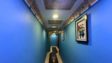 A hallway with blue walls, a tiled floor, and framed artwork on the walls.