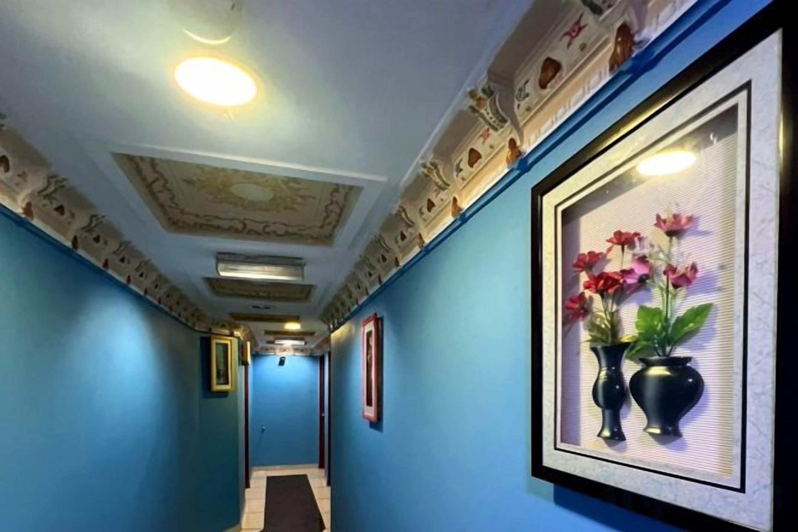 A hallway with blue walls, framed artwork, and a ceiling with decorative moldings.