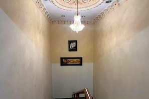 Ein Raum mit einer Chandelüster, einem gerahmten Bild und einem Sessel.