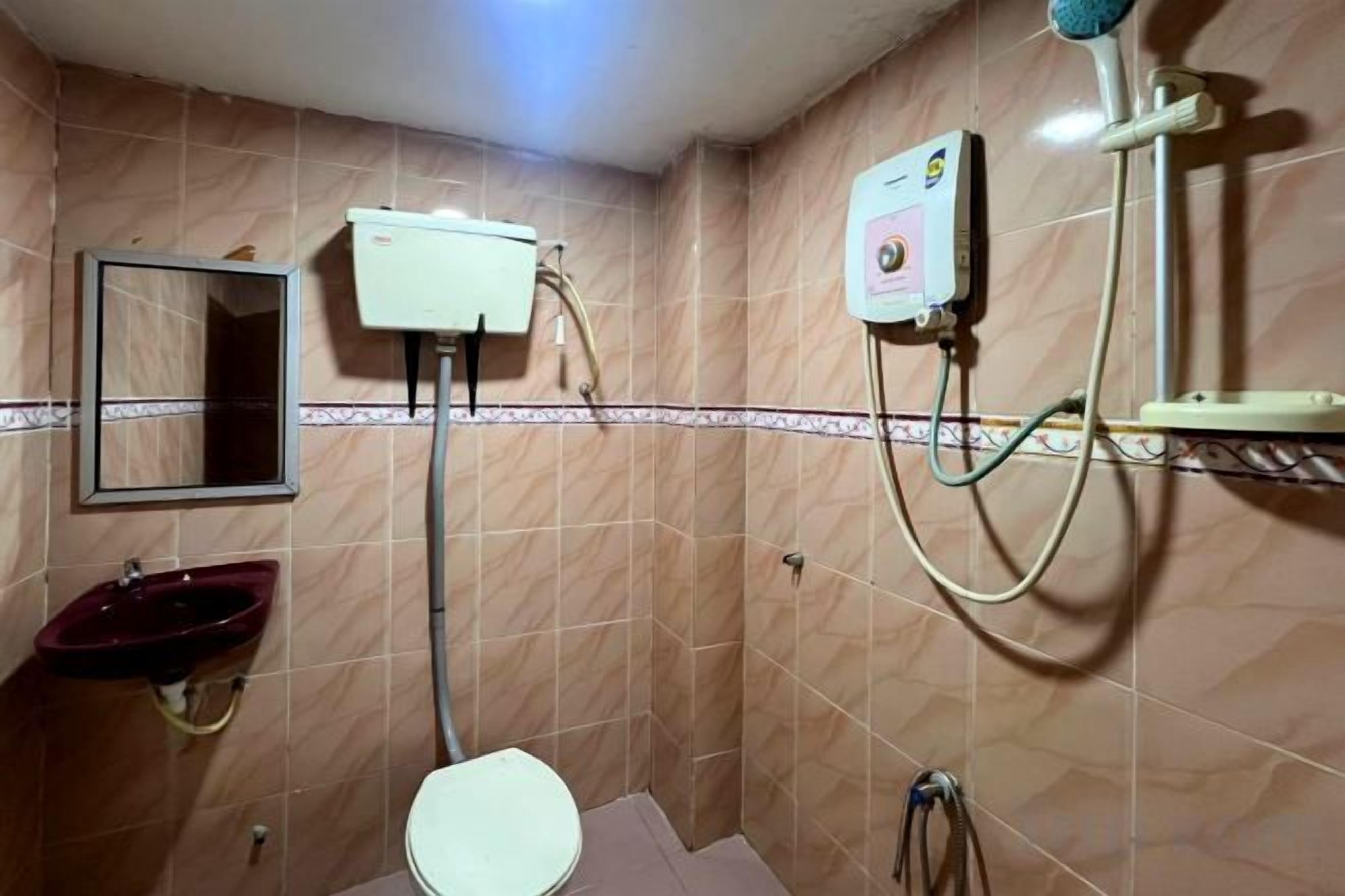 A bathroom with a toilet, sink, mirror, and shower.