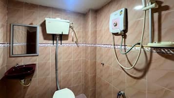A bathroom with a toilet, sink, mirror, and shower.