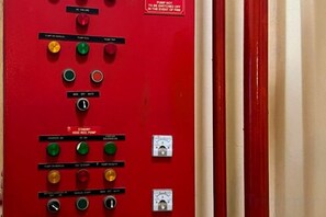 A red control panel with various switches and indicators, including a warning label.