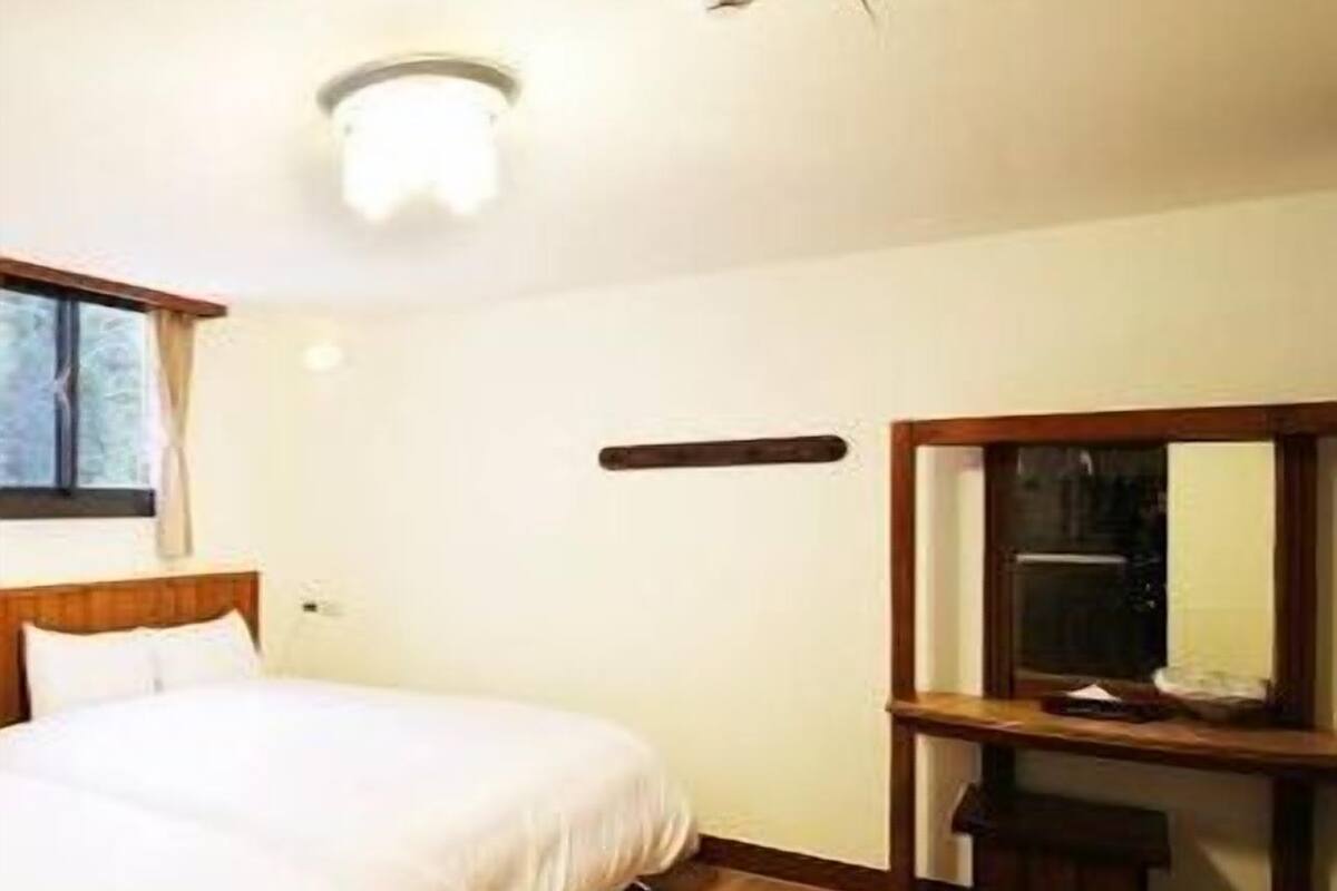 A hotel room with a bed, a desk, and a mirror.