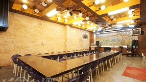 A conference room with a long table, chairs, ceiling lights, a projector screen, and a mural on the wall. - Gemlu Hotel (Lugu)