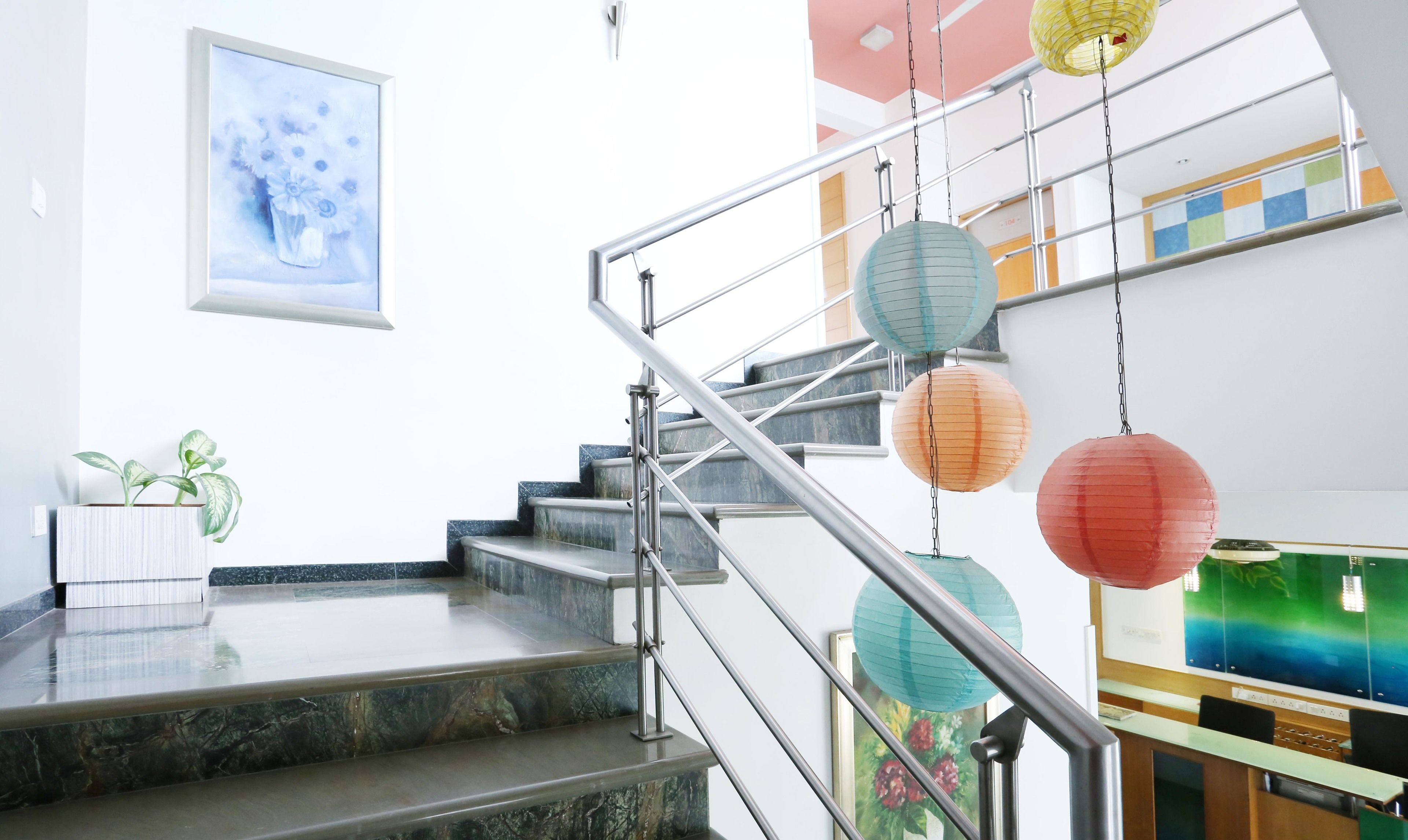 A staircase with metal railings, a potted plant, and hanging paper lanterns.