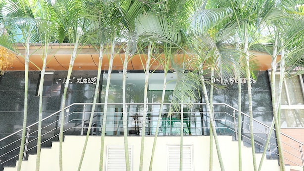 Un bâtiment moderne doté d’un escalier en verre, entouré de grands plants de bambou.