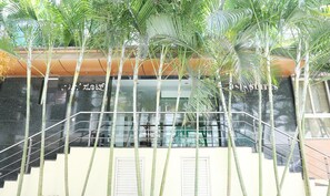 A modern building with a glass staircase, surrounded by tall bamboo plants. - Treebo Edha Suites Koramangala (Bengaluru)