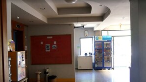 Un couloir avec un distributeur automatique, un tableau d’affichage, un réfrigérateur et un autre distributeur automatique.