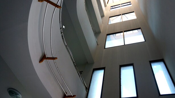 Un intérieur à plusieurs niveaux, doté d’un escalier central, de nombreuses fenêtres et d’une verrière.
