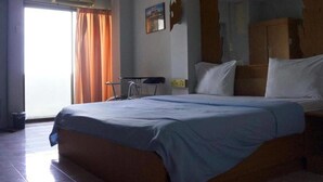 Une chambre d’hôtel avec un lit, une chaise, un bureau et une armoire.