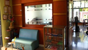 Une pièce avec un canapé bleu, une vitrine en verre contenant des cartes postales et une fenêtre donnant sur la rue.