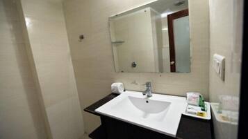 A bathroom with a white sink, dark countertop, and a mirror above it.