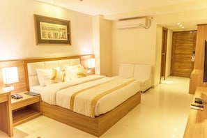 Habitación de hotel con una cama grande, mesitas de noche, un escritorio, un equipo de aire acondicionado y un televisor.