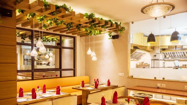 A restaurant with wooden booths, hanging plants, and pendant lighting. - Sangai Continental The Boutique Hotel (Imphal)