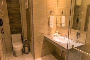 Un baño moderno con cabina de ducha de vidrio, inodoro, lavabo con tocador y espejo.