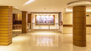 A hotel lobby with a polished floor, wooden columns, and a large artwork on the wall. - Sangai Continental The Boutique Hotel (Imphal)