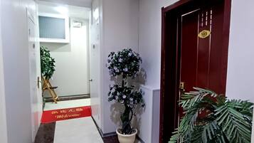 Un pasillo con un felpudo rojo, una planta en maceta y una puerta con el signo de número.