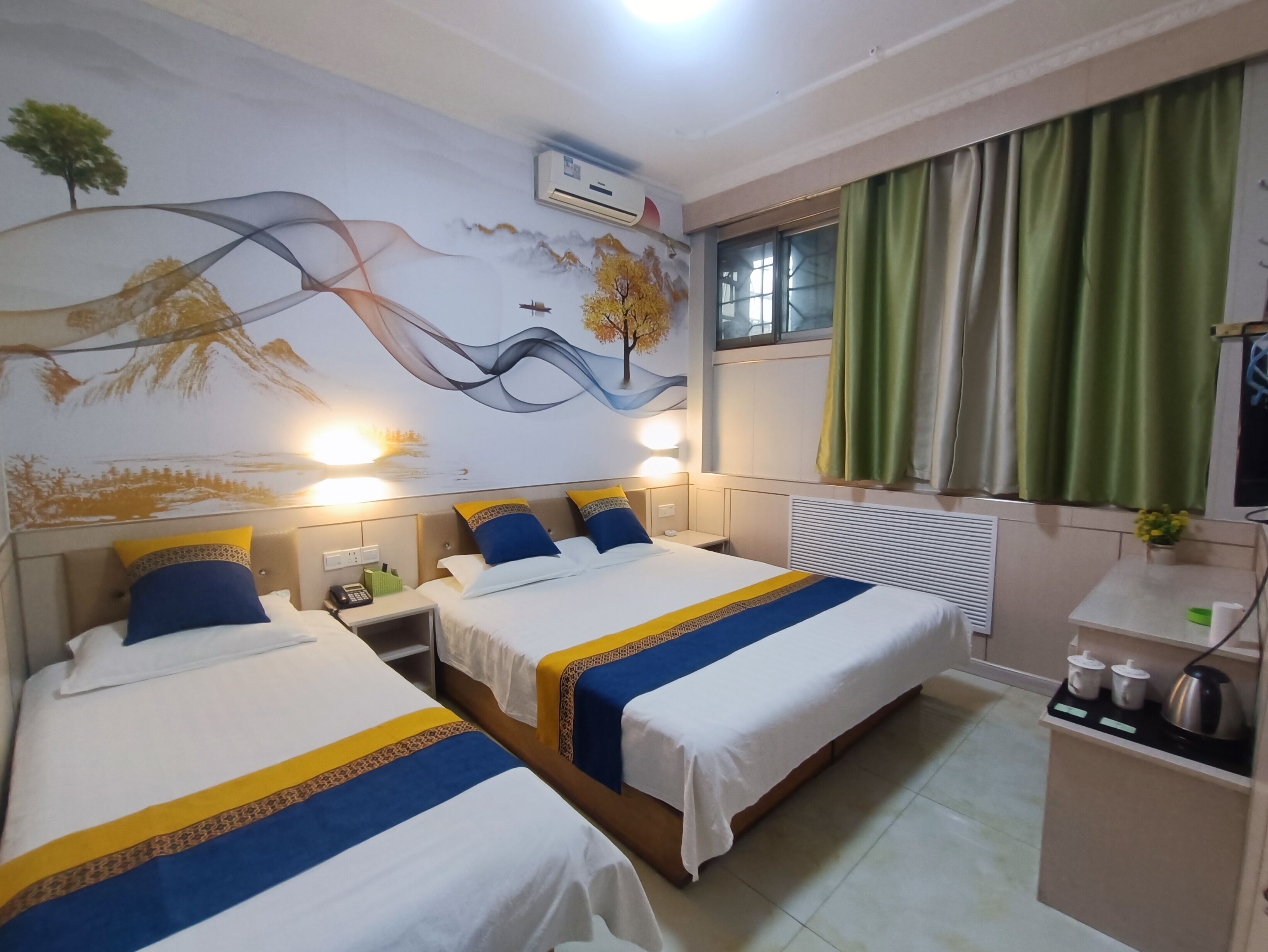 Een hotelkamer met twee bedden, een muurschildering, een raam met gordijnen en een klein tafeltje met waterkoker en kopjes.