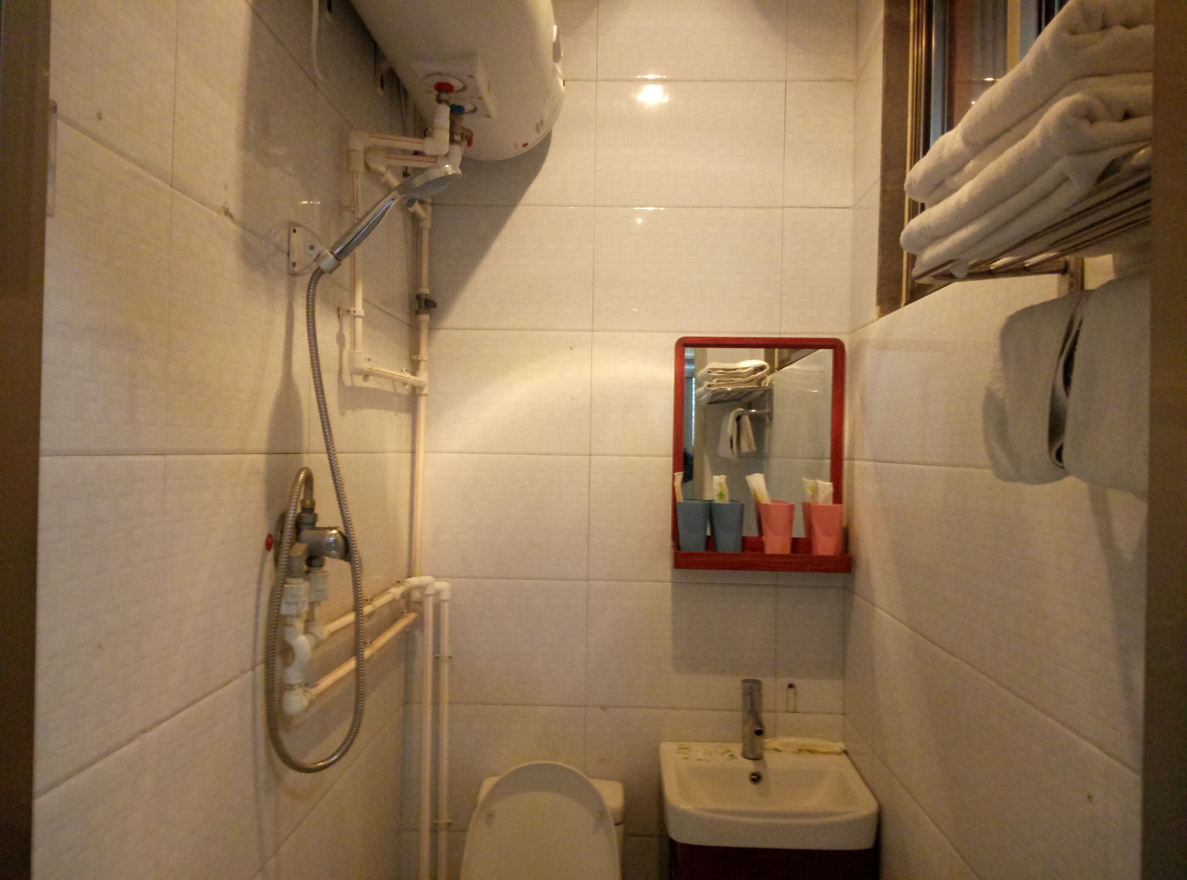 A small bathroom with a toilet, sink, and a mirror with a red frame.