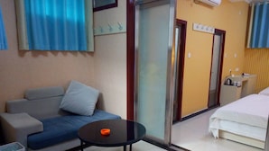 Habitación de hotel con sofá, una mesita redonda, cama y un separador de vidrio.
