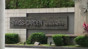 A sign for SWISS-GARDEN RESIDENCES with a stone facade and greenery in front. - Queens Service Suite at Swiss Garden Residences (Kuala Lumpur)